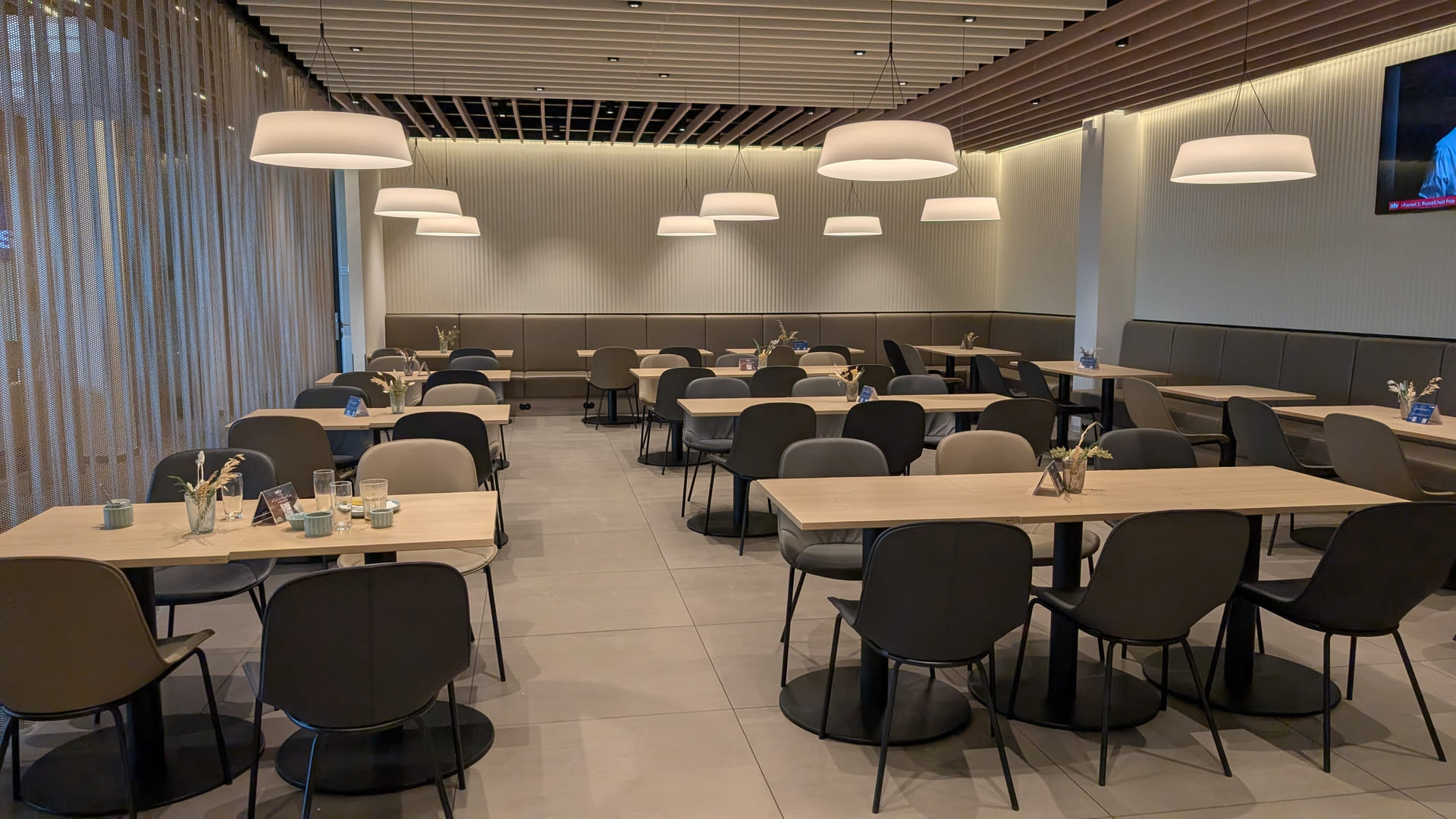 Essbereich der DUS Rhein Lounge mit Holztischen und Pendelleuchten